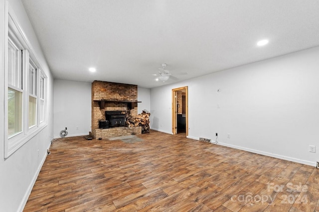 living room featuring hardwood / wood-style floors, ceiling fan, a textured ceiling, and a brick fireplace