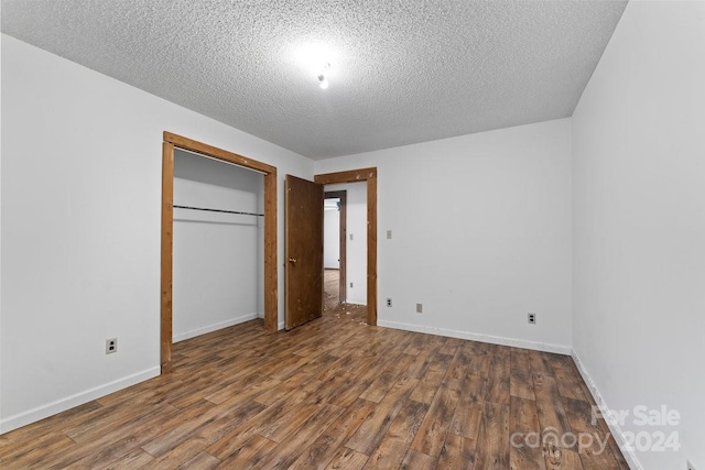 unfurnished bedroom with a textured ceiling, a closet, and dark wood-type flooring