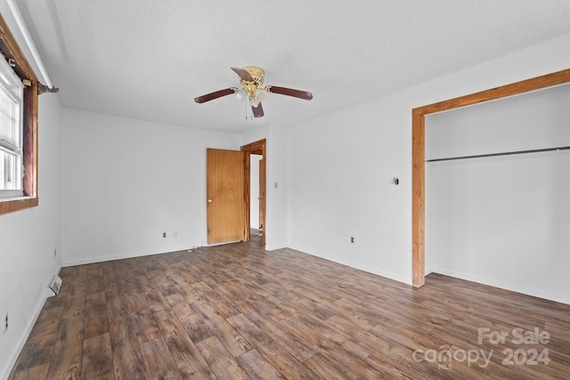 unfurnished bedroom featuring a textured ceiling, ceiling fan, dark wood-type flooring, and a closet