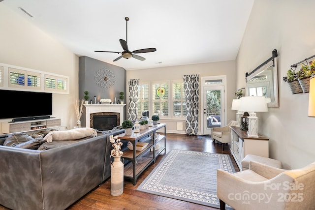 living room featuring a barn door, dark hardwood / wood-style floors, and ceiling fan