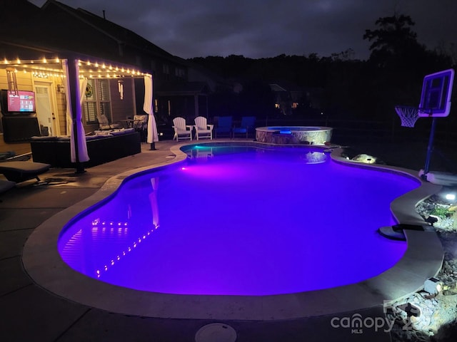 pool at twilight with an in ground hot tub and a patio area