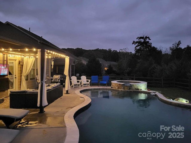 pool at dusk featuring a patio area and an in ground hot tub