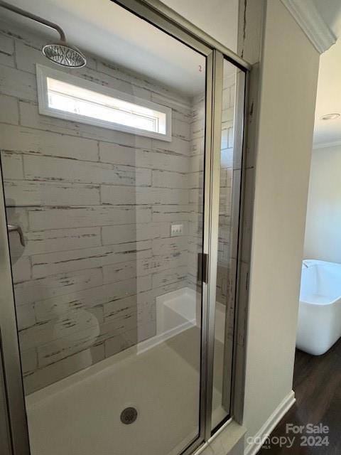 bathroom featuring wood-type flooring, a shower with shower door, and ornamental molding