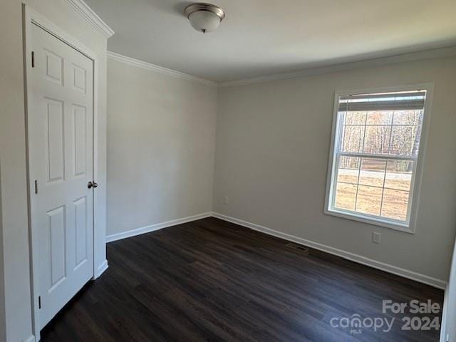 empty room with dark hardwood / wood-style floors and crown molding