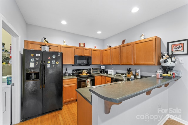 kitchen with a kitchen breakfast bar, black appliances, kitchen peninsula, and washer / clothes dryer