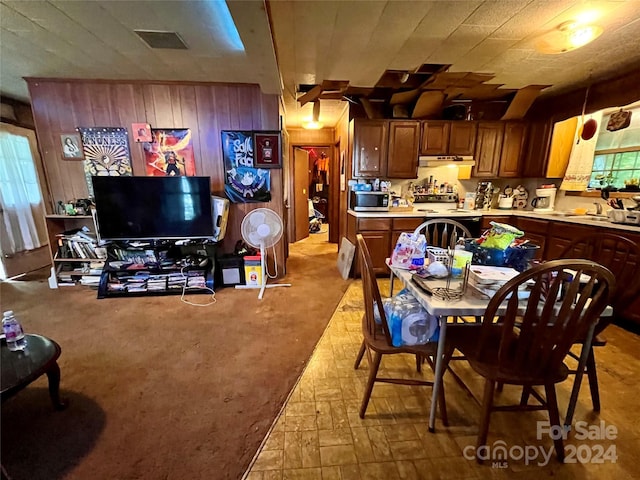 dining space featuring wooden walls and light carpet