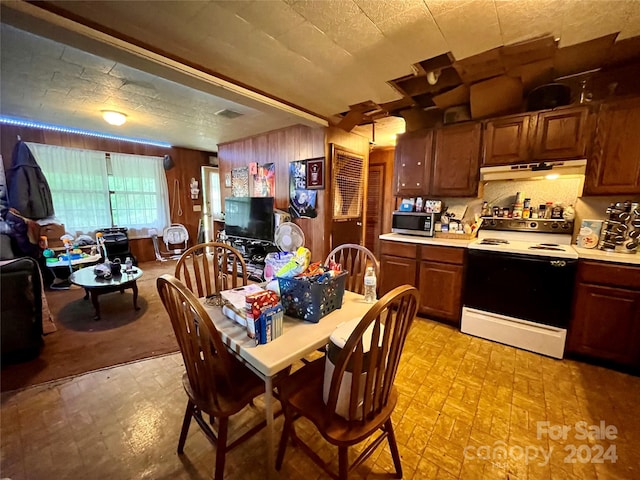 kitchen with electric range oven and wood walls