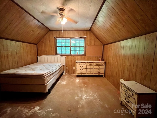 unfurnished bedroom with concrete flooring, vaulted ceiling, wooden walls, and ceiling fan