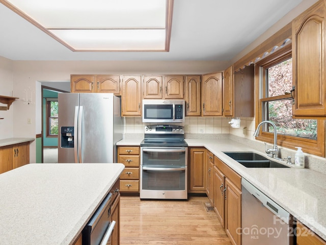 kitchen with appliances with stainless steel finishes, light hardwood / wood-style floors, tasteful backsplash, and sink