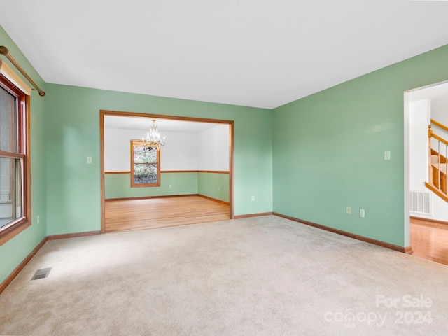 empty room with carpet and an inviting chandelier