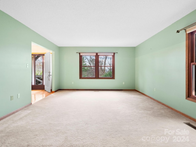 carpeted empty room featuring a textured ceiling