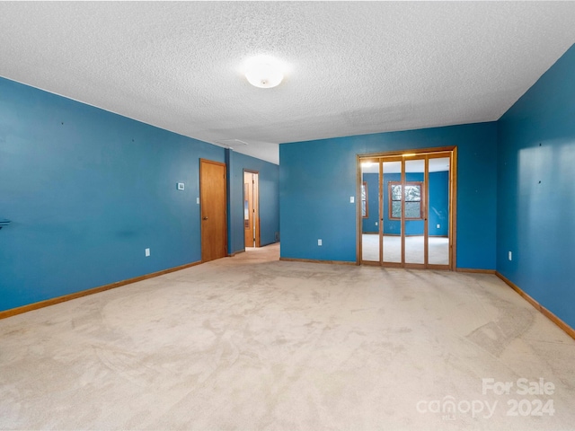 carpeted empty room with a textured ceiling