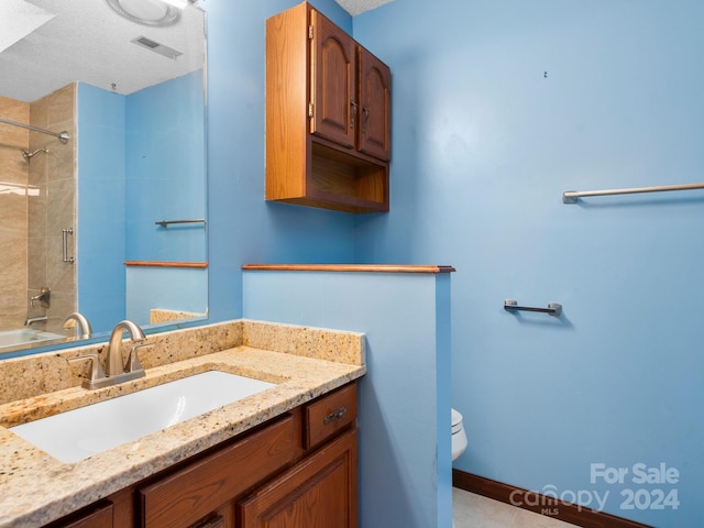 full bathroom with vanity, a textured ceiling, toilet, and tiled shower / bath combo