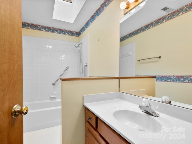 bathroom with a skylight, vanity, and tiled shower / bath combo