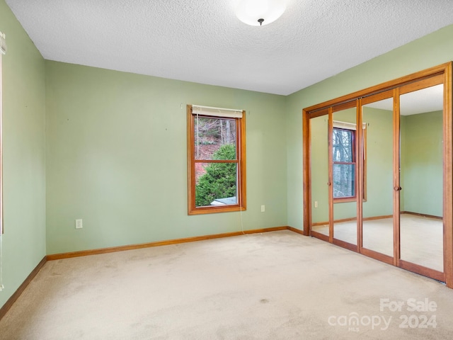 empty room with light carpet and a textured ceiling