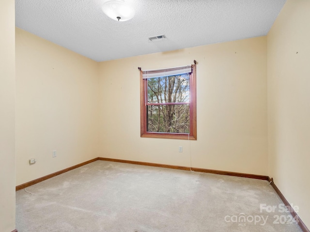 empty room featuring a textured ceiling and light carpet