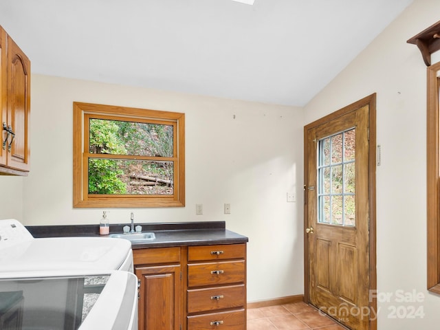 clothes washing area featuring cabinets, light tile patterned floors, washer and clothes dryer, and sink