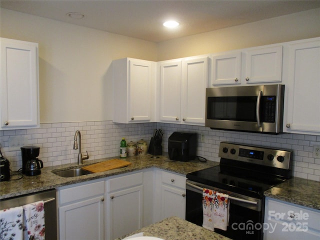 kitchen featuring sink, stainless steel appliances, tasteful backsplash, white cabinets, and stone countertops