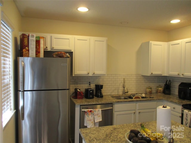 kitchen featuring light stone countertops, appliances with stainless steel finishes, and white cabinets