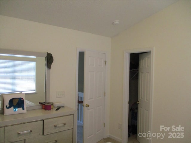 unfurnished bedroom featuring vaulted ceiling and a spacious closet