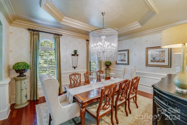 dining area featuring ornamental molding, wood-type flooring, a tray ceiling, and a notable chandelier