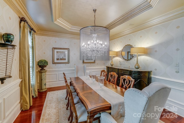 dining area with wallpapered walls, a raised ceiling, wainscoting, dark wood-type flooring, and a chandelier