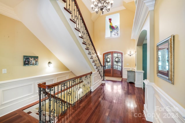 entryway with an inviting chandelier, a high ceiling, dark hardwood / wood-style flooring, french doors, and ornamental molding