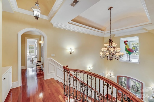 hallway with a notable chandelier, crown molding, and hardwood / wood-style floors