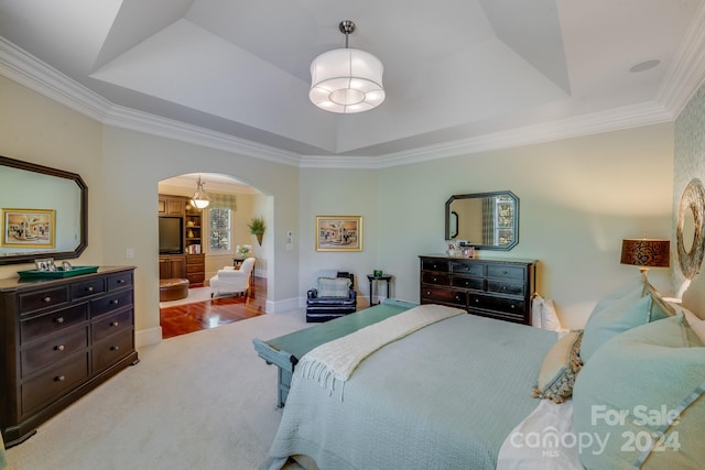 bedroom featuring ornamental molding, a raised ceiling, and carpet flooring