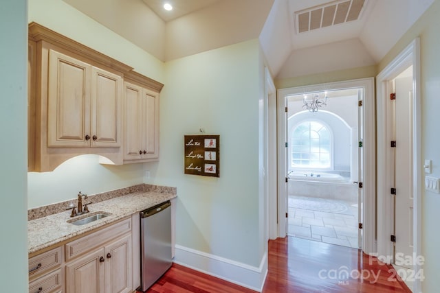 kitchen featuring visible vents, light stone counters, vaulted ceiling, stainless steel dishwasher, and a sink