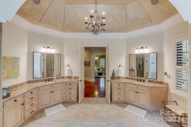 bathroom featuring vanity, an inviting chandelier, a tray ceiling, and ornamental molding