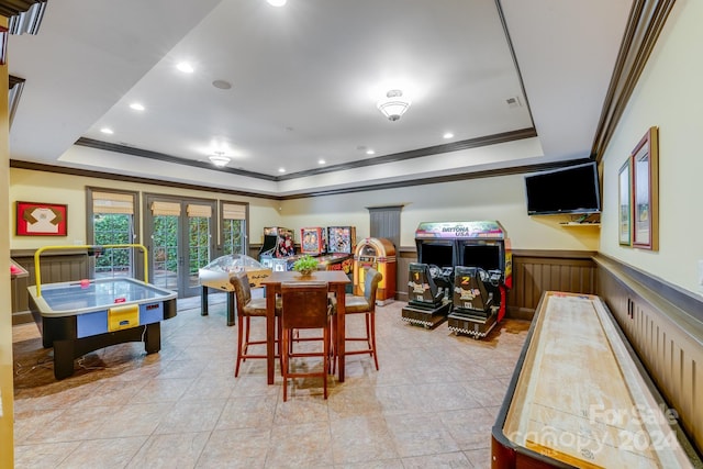 playroom featuring wainscoting, ornamental molding, a raised ceiling, and french doors