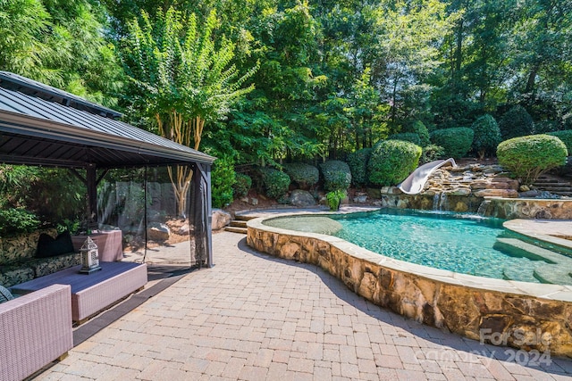 pool with a water slide, a patio, and a gazebo