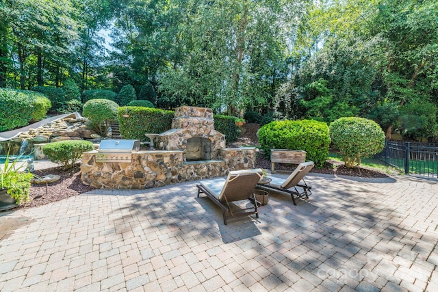 view of patio / terrace featuring an outdoor stone fireplace and an outdoor kitchen