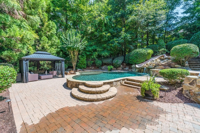 view of swimming pool featuring a patio area, a gazebo, and a water slide