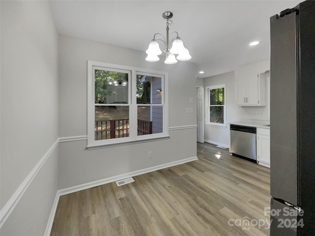 unfurnished dining area featuring light hardwood / wood-style floors and a chandelier