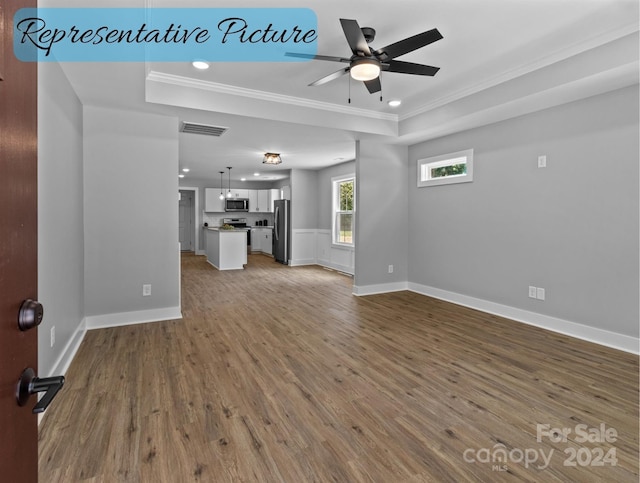 unfurnished living room featuring ceiling fan, ornamental molding, wood-type flooring, and a raised ceiling