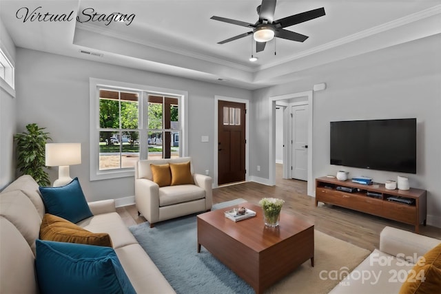 living room with ceiling fan, ornamental molding, light hardwood / wood-style flooring, and a tray ceiling