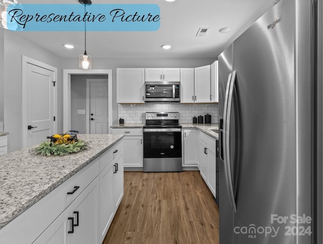 kitchen with hardwood / wood-style floors, appliances with stainless steel finishes, decorative light fixtures, white cabinetry, and backsplash