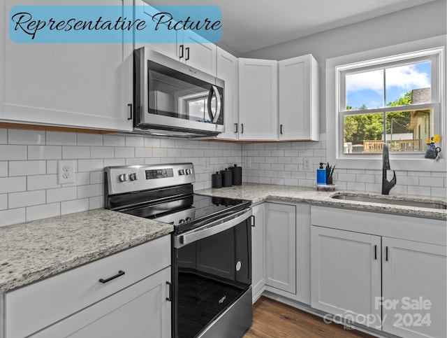 kitchen featuring tasteful backsplash, sink, white cabinetry, light stone countertops, and appliances with stainless steel finishes