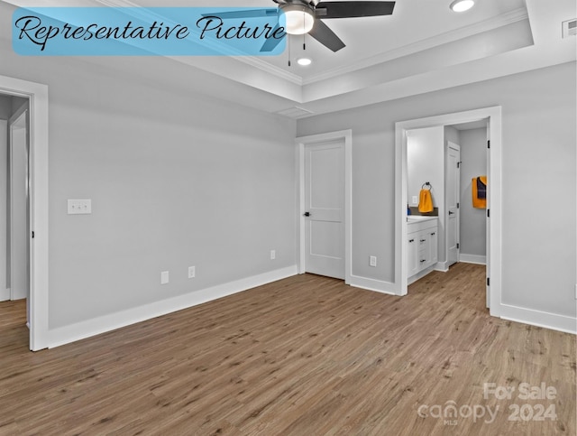 unfurnished bedroom with ensuite bath, a raised ceiling, ceiling fan, light hardwood / wood-style flooring, and crown molding