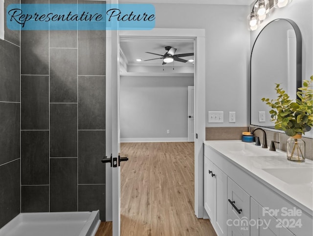 bathroom featuring ceiling fan, tiled shower, hardwood / wood-style flooring, and vanity