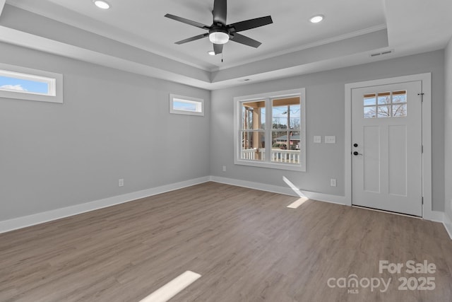 foyer featuring light hardwood / wood-style flooring, a raised ceiling, ceiling fan, and plenty of natural light