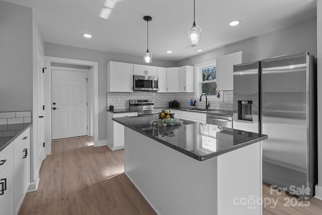 kitchen with a kitchen island, appliances with stainless steel finishes, sink, white cabinets, and light hardwood / wood-style flooring