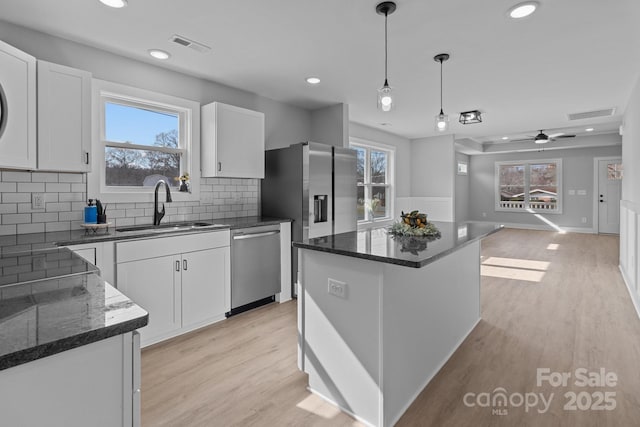 kitchen featuring sink, a kitchen island, pendant lighting, stainless steel appliances, and white cabinets