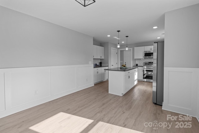 kitchen featuring decorative light fixtures, a kitchen island, white cabinets, stainless steel appliances, and backsplash