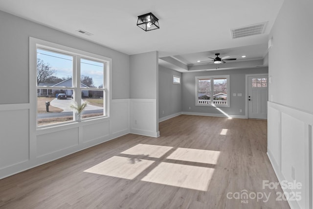 unfurnished room featuring a wealth of natural light, light wood-type flooring, and a tray ceiling