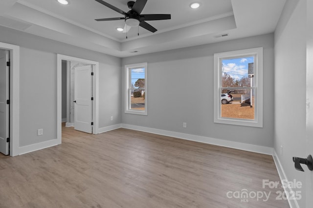 unfurnished bedroom featuring a raised ceiling, light hardwood / wood-style floors, and multiple windows