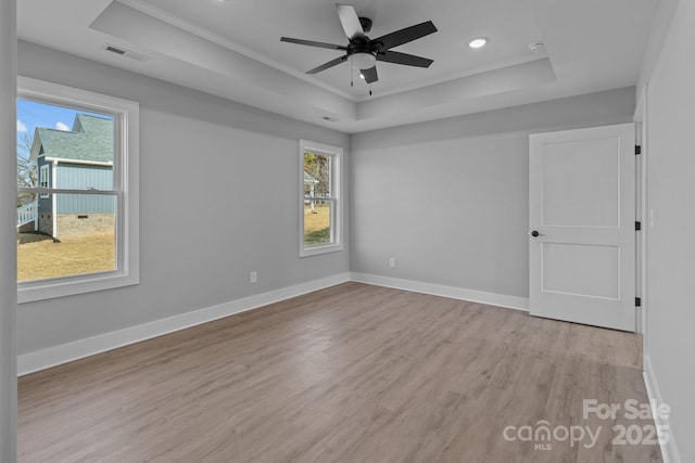 spare room featuring a tray ceiling, light hardwood / wood-style flooring, ornamental molding, and ceiling fan