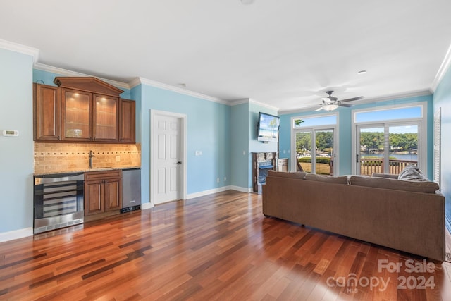 living room with dark hardwood / wood-style floors, beverage cooler, ornamental molding, sink, and ceiling fan